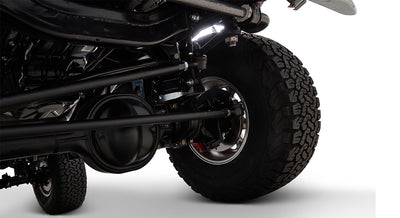 Suspension and axle close-up with rugged tire on Classic Ford Bronco against white background.