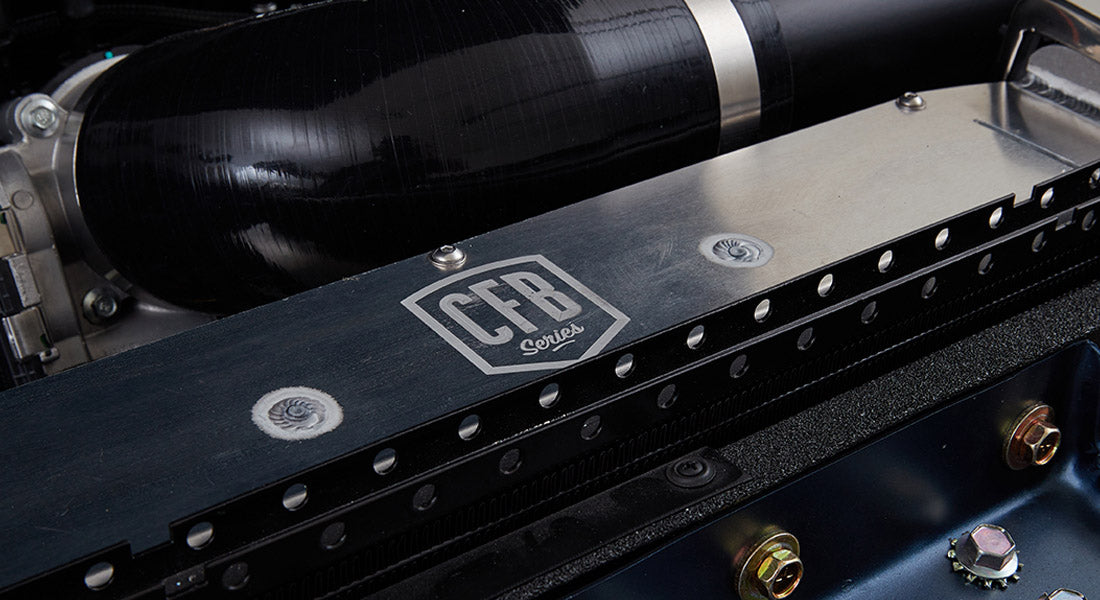 Close-up of black metal component with 'CFB Series' logo and mechanical parts inside a Classic Ford Bronco