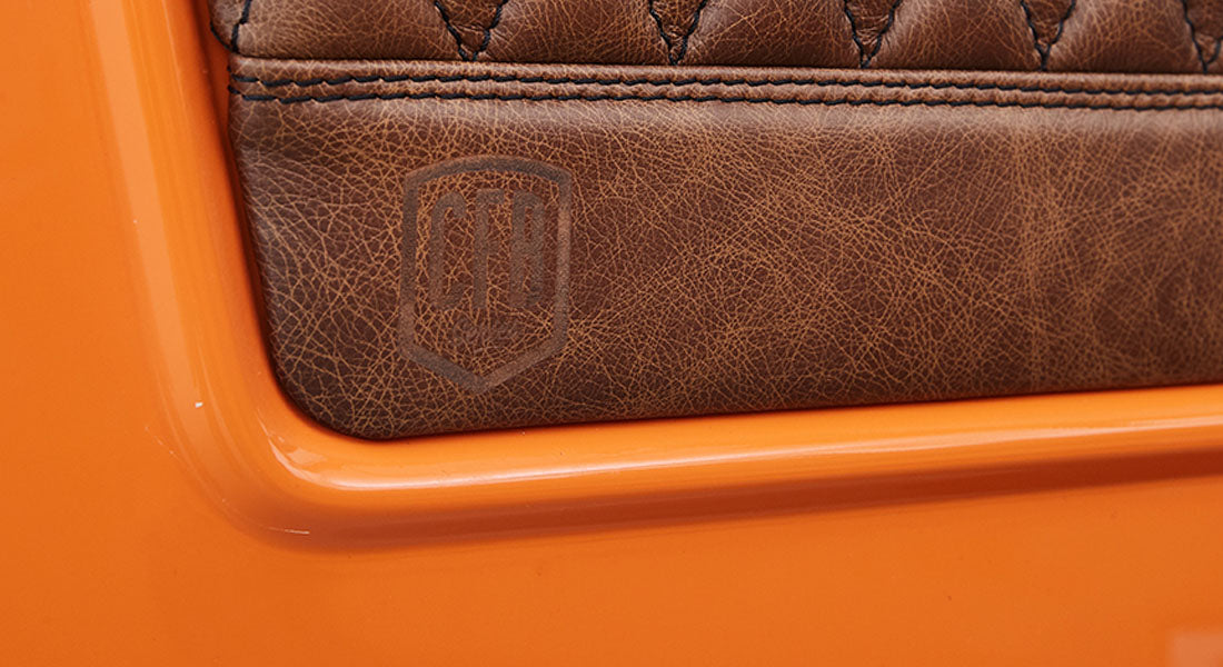 Brown leather panel embossed with CFB logo on a bright orange classic vehicle body