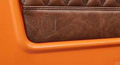 Brown leather panel embossed with CFB logo on a bright orange classic vehicle body