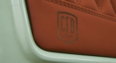 Close-up of the CFB Series logo embossed on tan leather upholstery inside a Classic Ford Bronco.