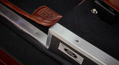 Black carpet floor mat with brown leather trim branded CFB Series and Ford metal trim plate