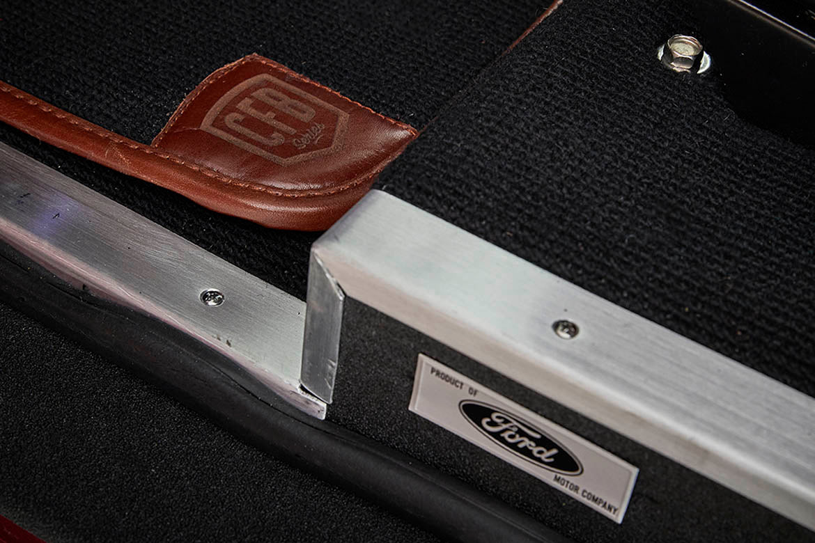 Ford Motor Company logo plaque and leather patch on black floor carpet inside a Classic Ford Bronco