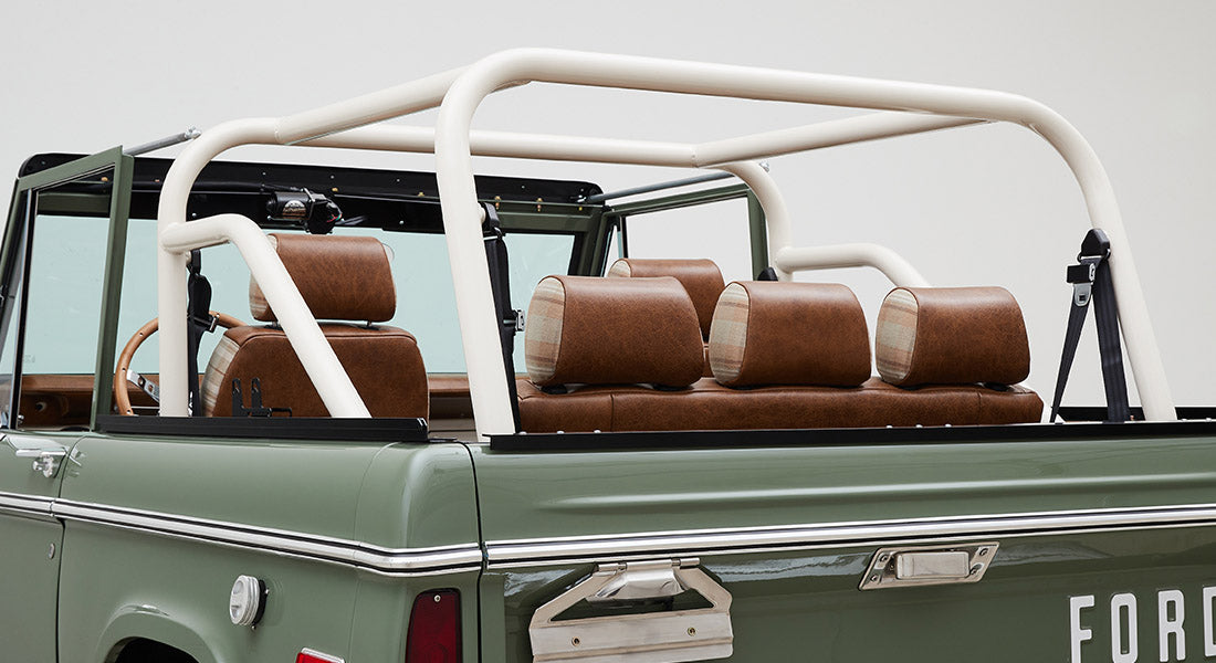Classic Ford Bronco with green exterior and white roll cage showing interior seating