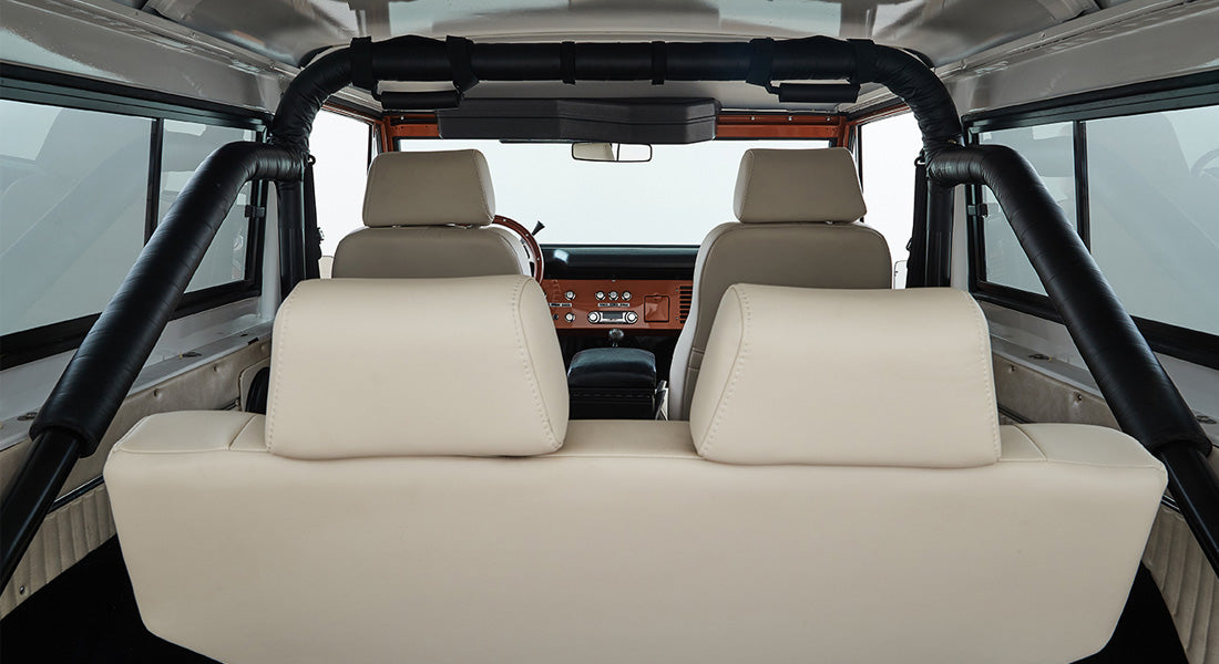 Rear interior view of Classic Ford Bronco showing cream seats and padded black roll cage