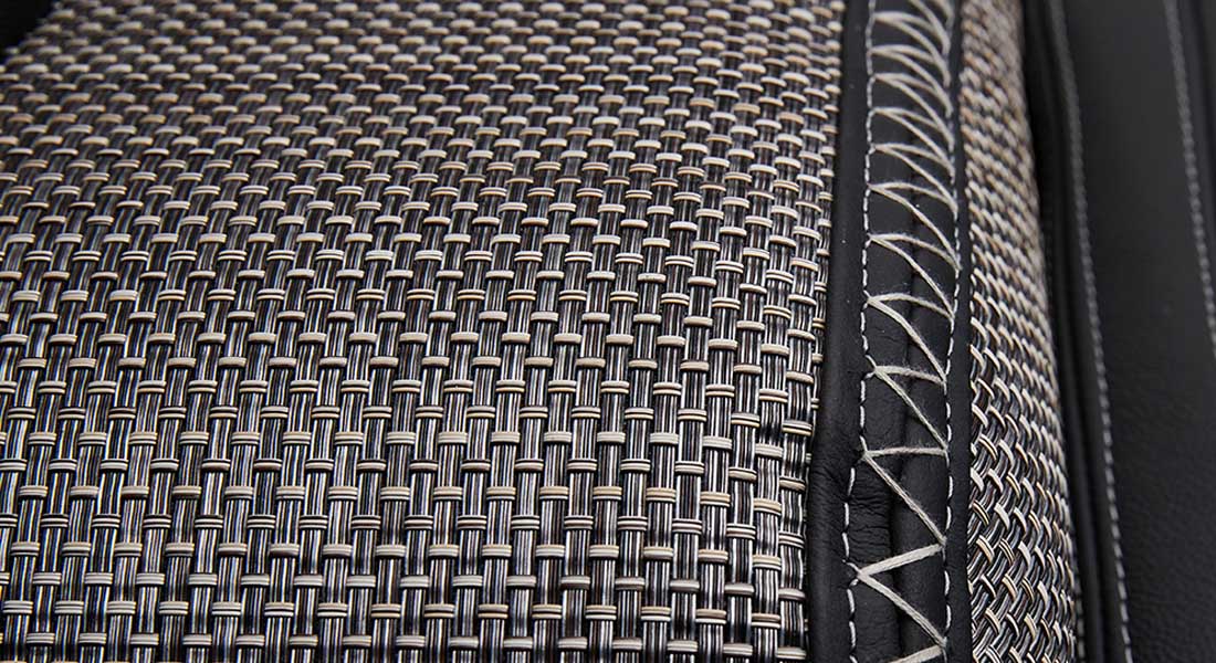 Detailed view of woven carpet featuring black leather with white stitching