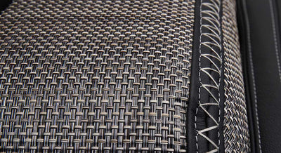 Detailed view of woven carpet featuring black leather with white stitching