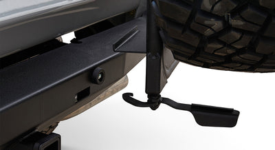 Close-up of a black metal carrier latch near a large off-road tire on a vehicle