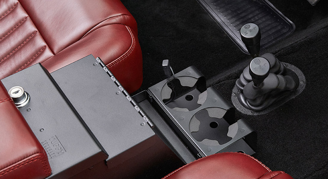 Black center console with cup holders situated between red leather seats and gear shifters