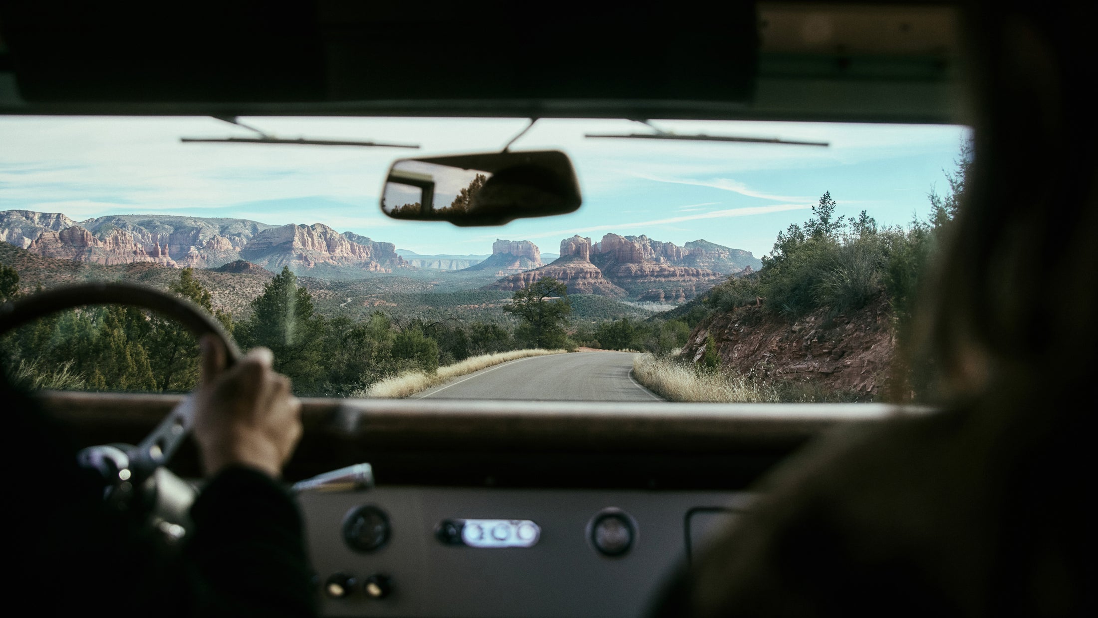 View from inside a vehicle driving on a winding road with mountainous terrain ahead