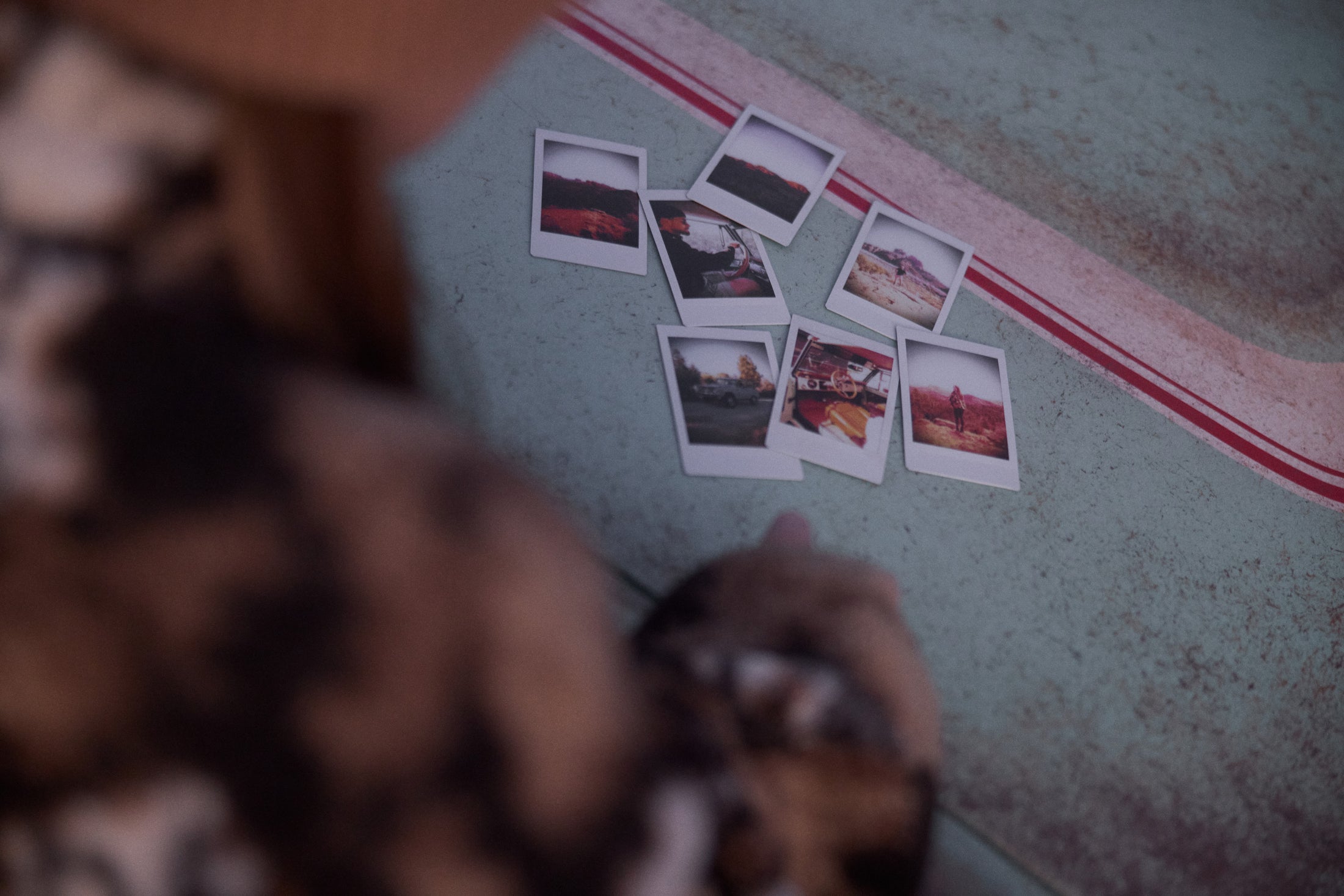 Person looking at a collection of instant photos on a weathered surface