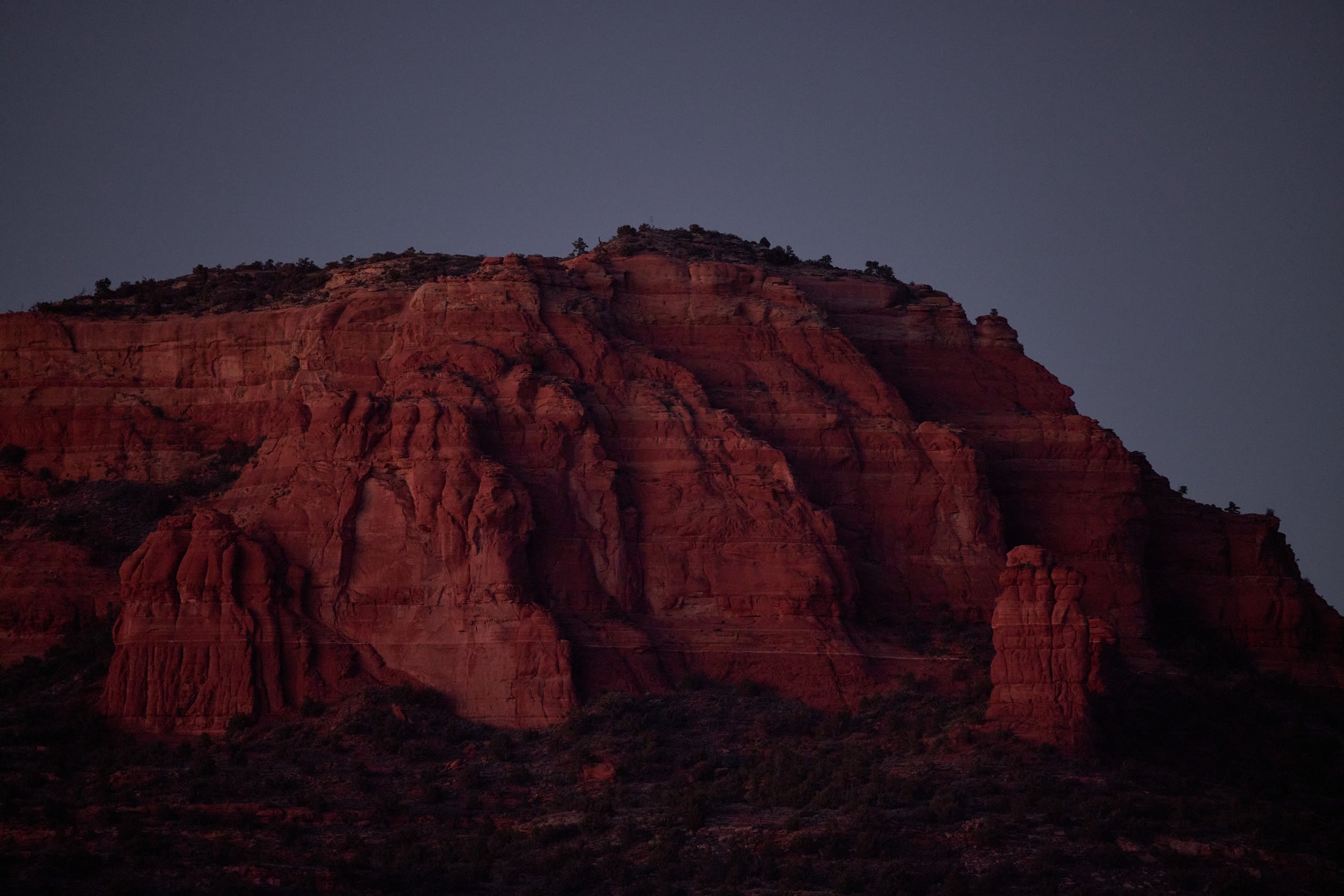 Red rocky mountain cliffs illuminated by moonlight against a dark sky