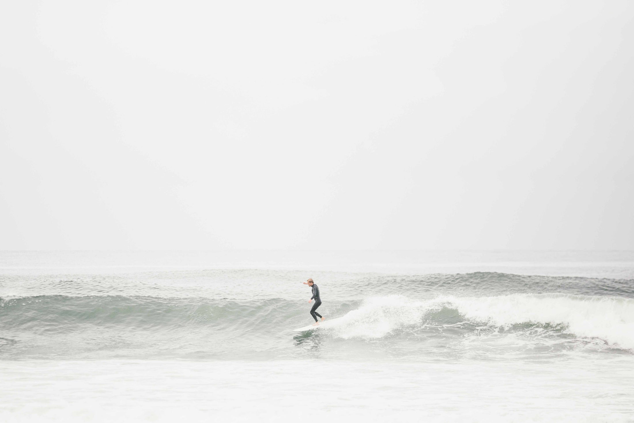Surfer riding small wave on ocean in wetsuit
