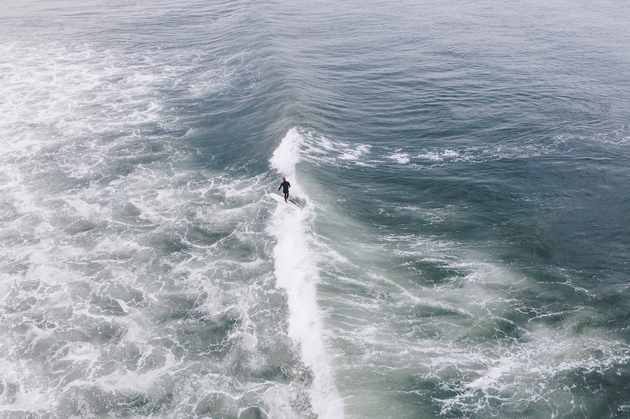 Surfer riding wave viewed from above near ocean shore