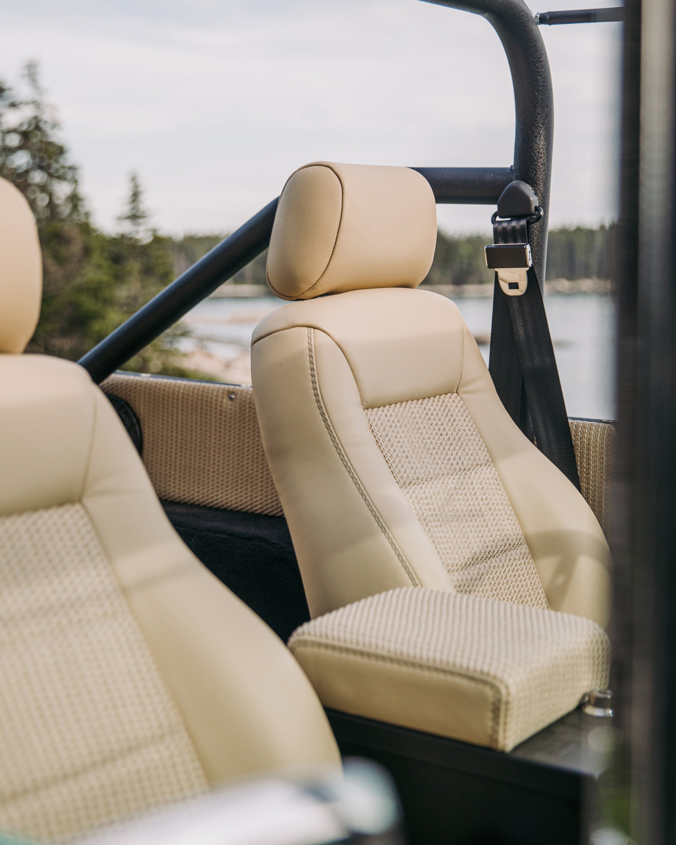 Close-up of beige vehicle seats with safety belt and roll cage