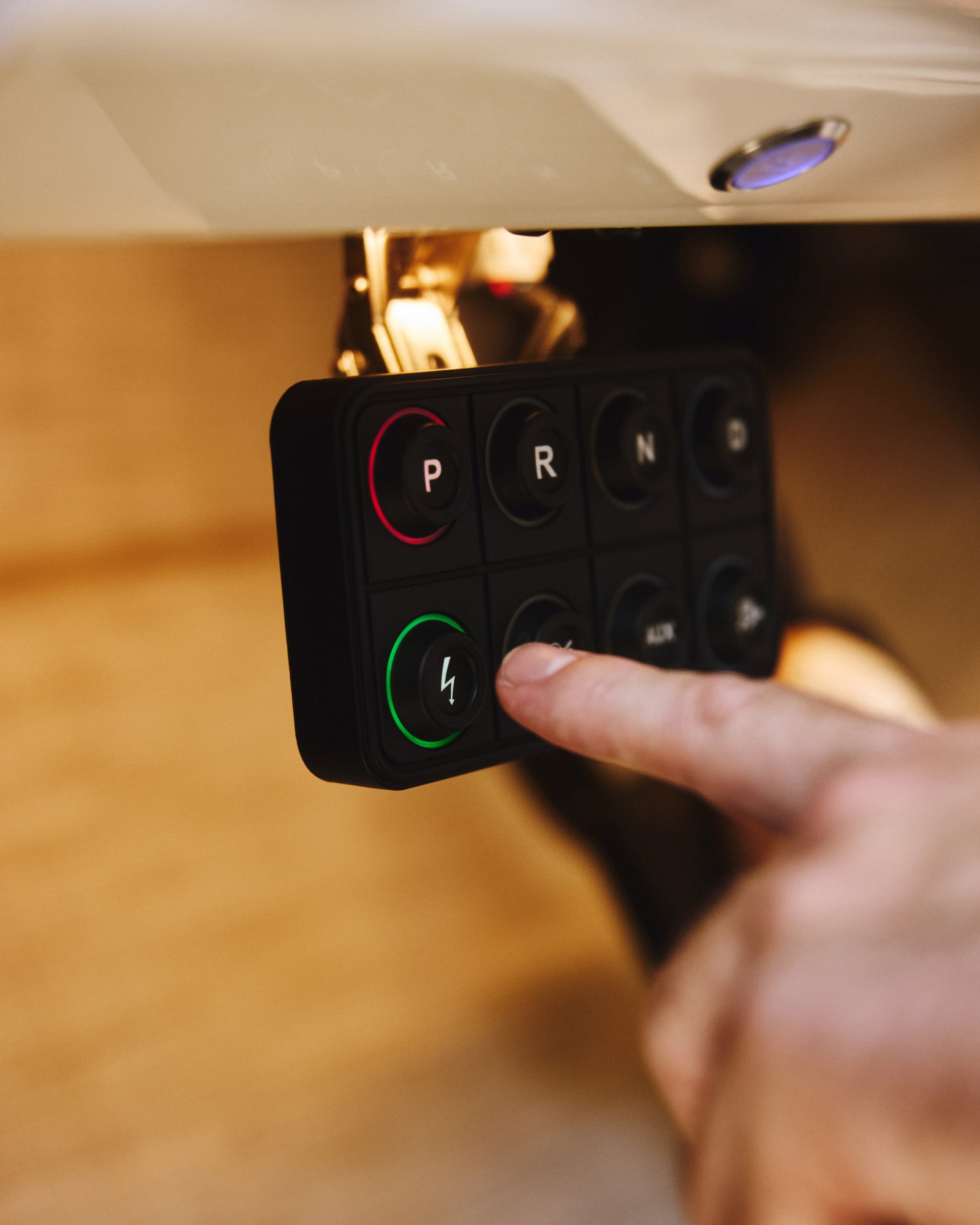Finger about to press a green button with a lightning bolt icon on a switch panel inside a vehicle