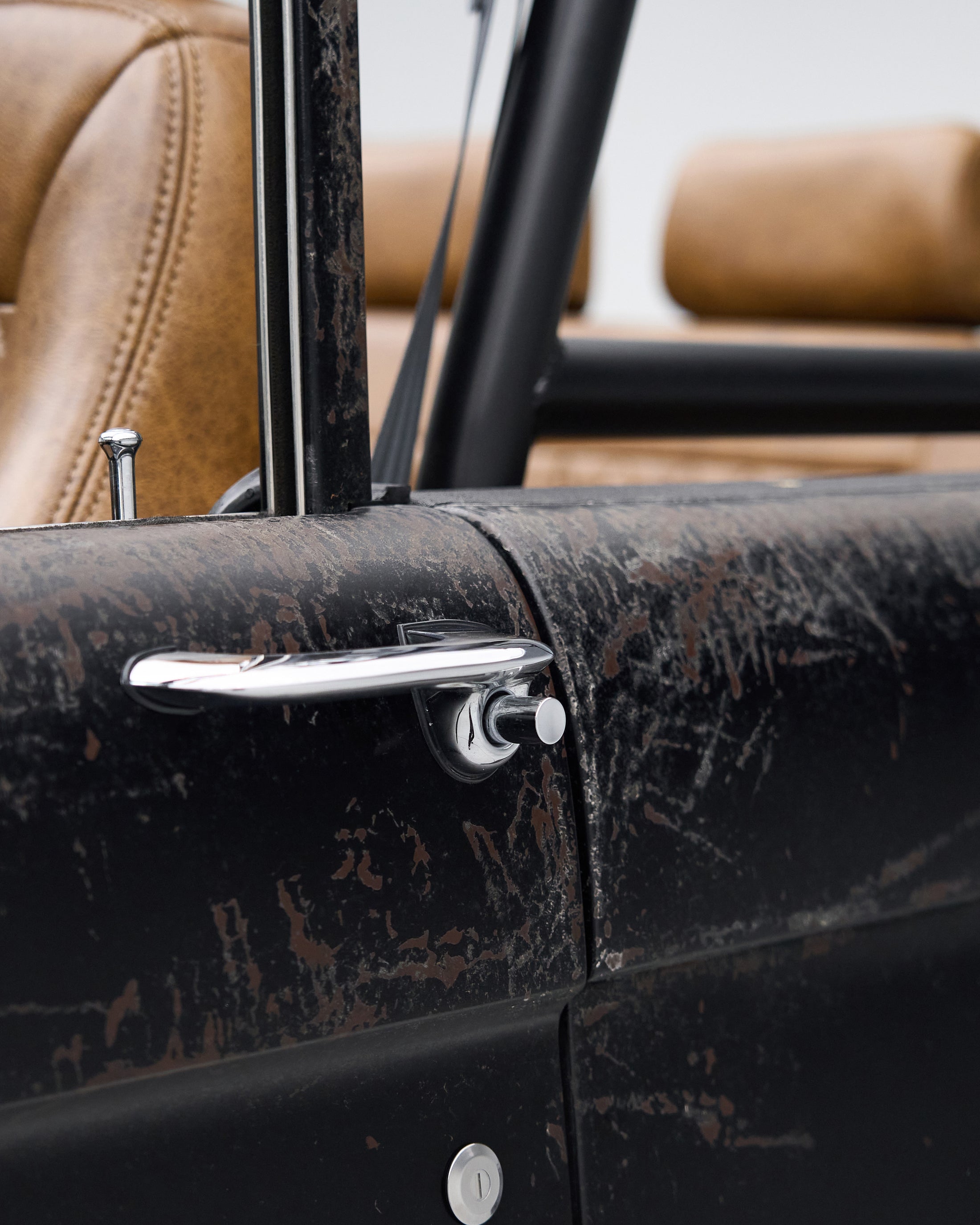 Close-up of door handle and primer-coated exterior paint showing patina on Classic Ford Bronco