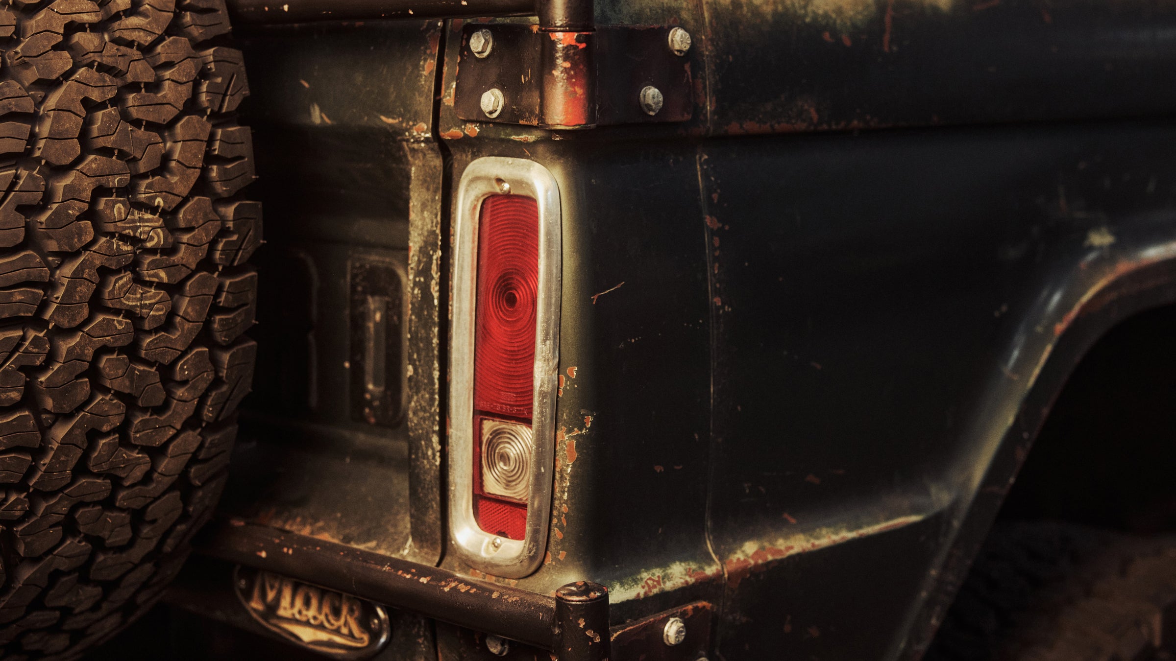 Close-up of a Classic Ford Bronco rear corner with off-road tire and worn tail light