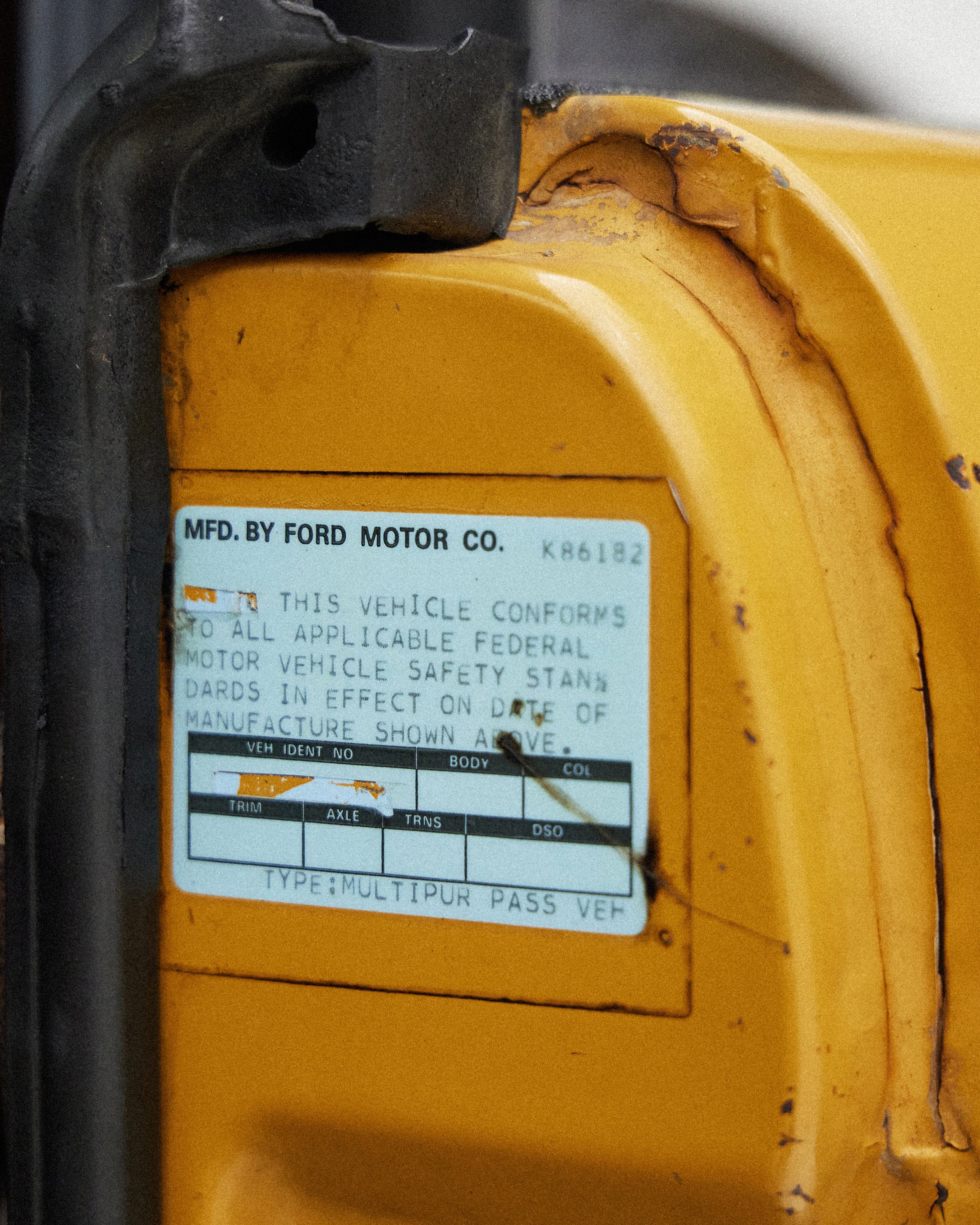Close-up of vehicle identification label on yellow painted metal surface