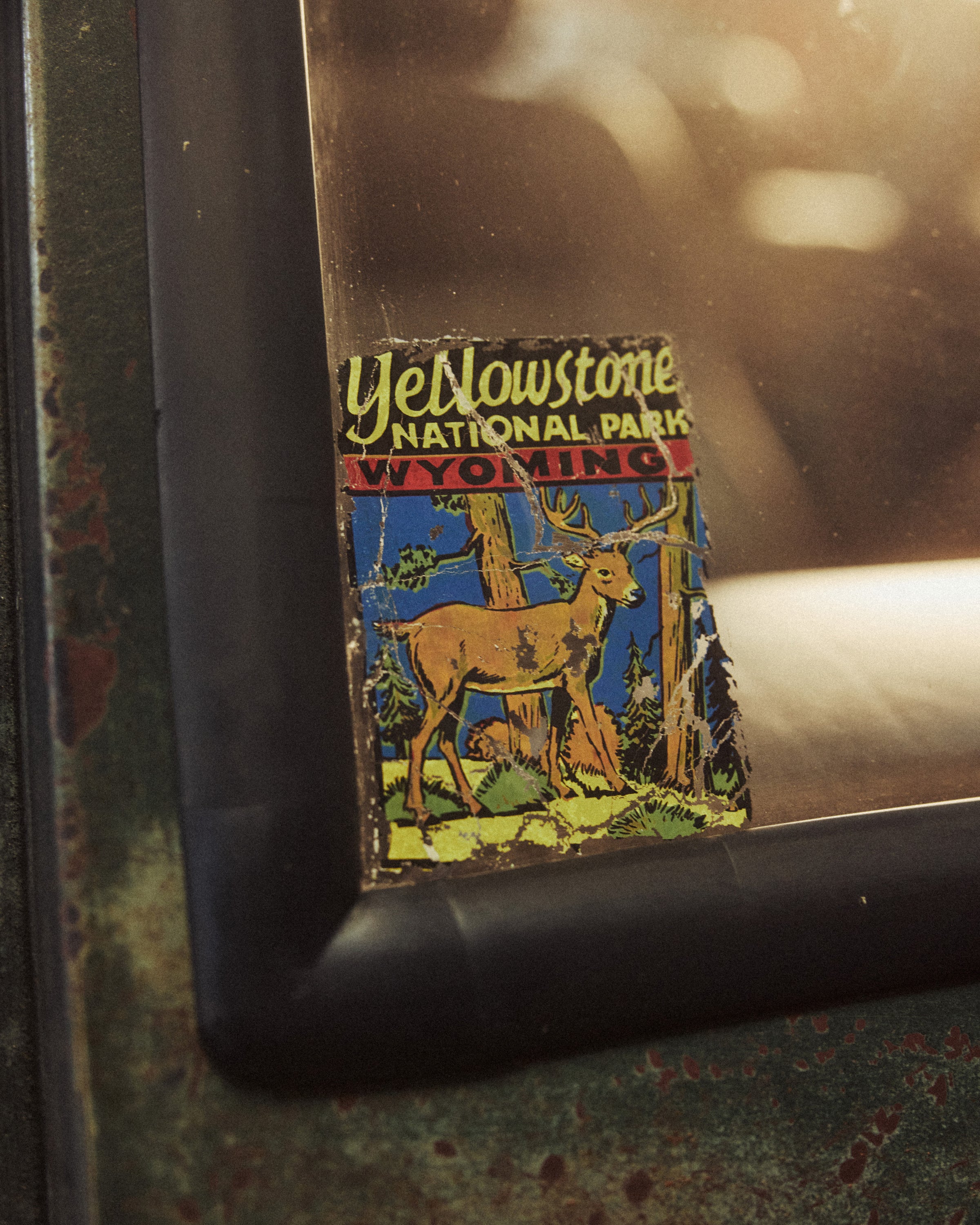 Worn Yellowstone National Park Wyoming sticker on green metal panel