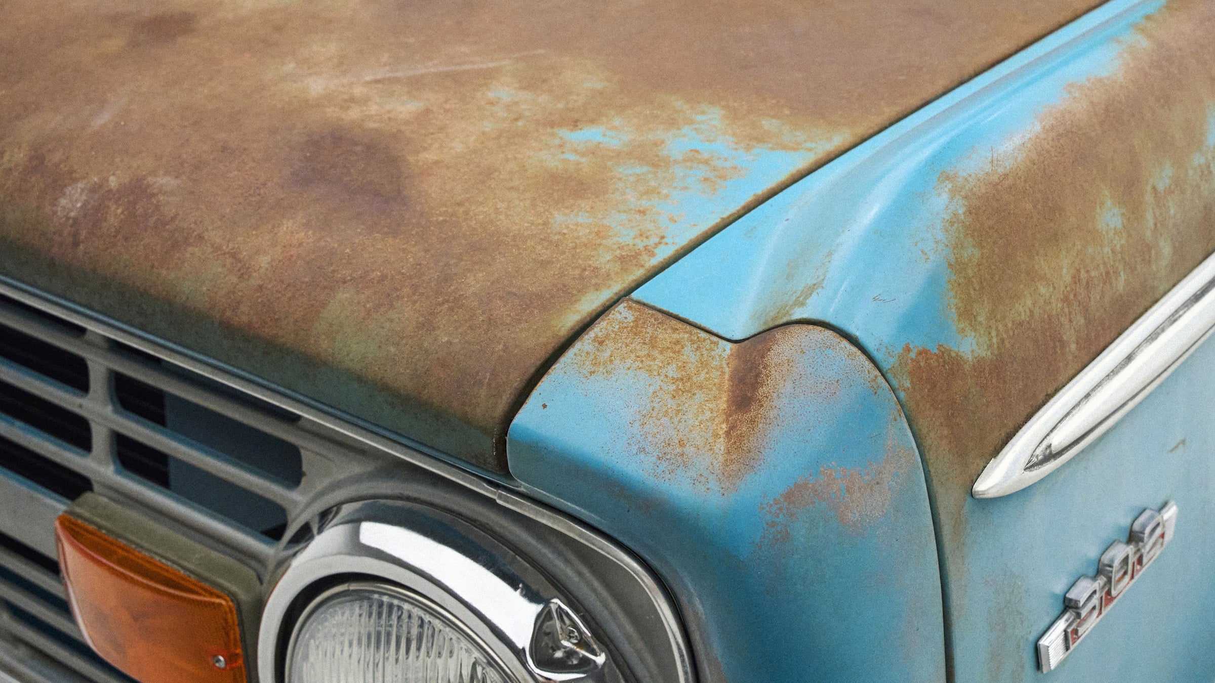 Close-up of rusty, weathered blue hood and front grille of Classic Ford Bronco