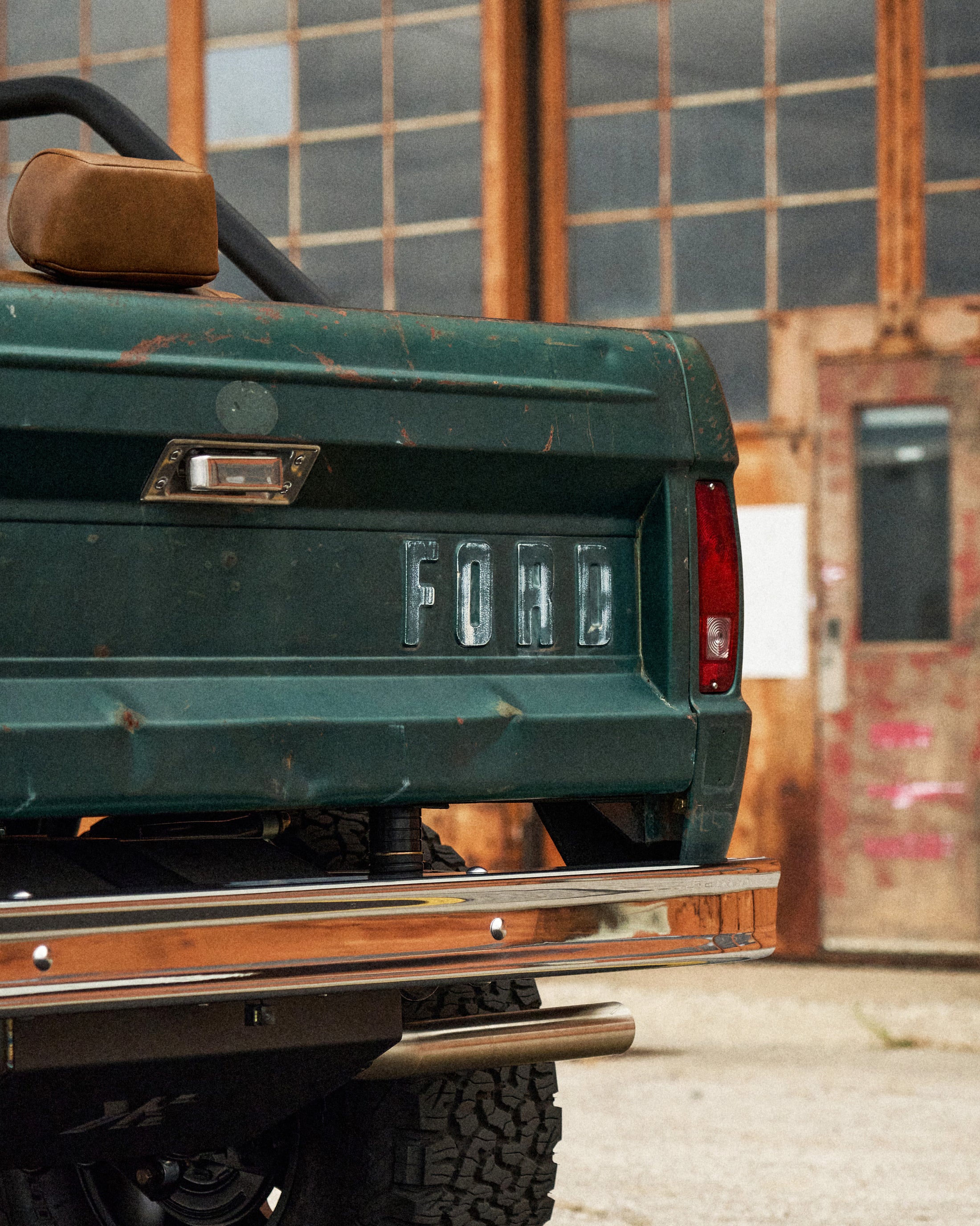 Rear of green Classic Ford Bronco showing chrome FORD emblem and tail light