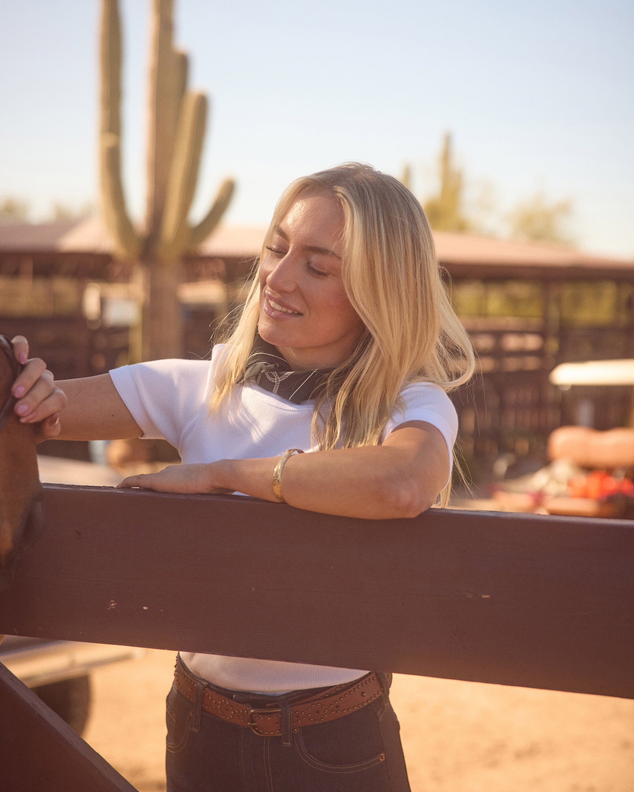 Smiling woman leaning on a wooden fence near a cactus plant