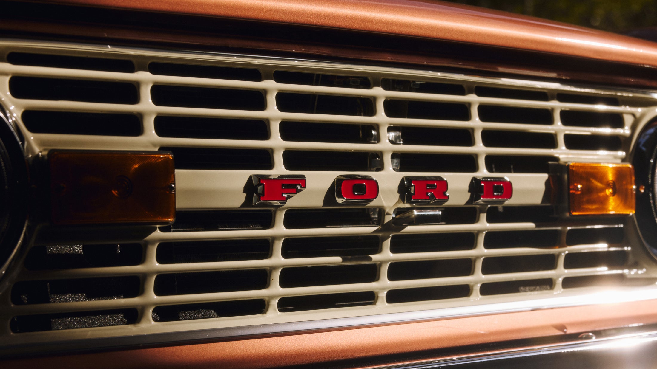 Close-up of a vintage FORD grille with amber side marker lights on a copper-colored vehicle.