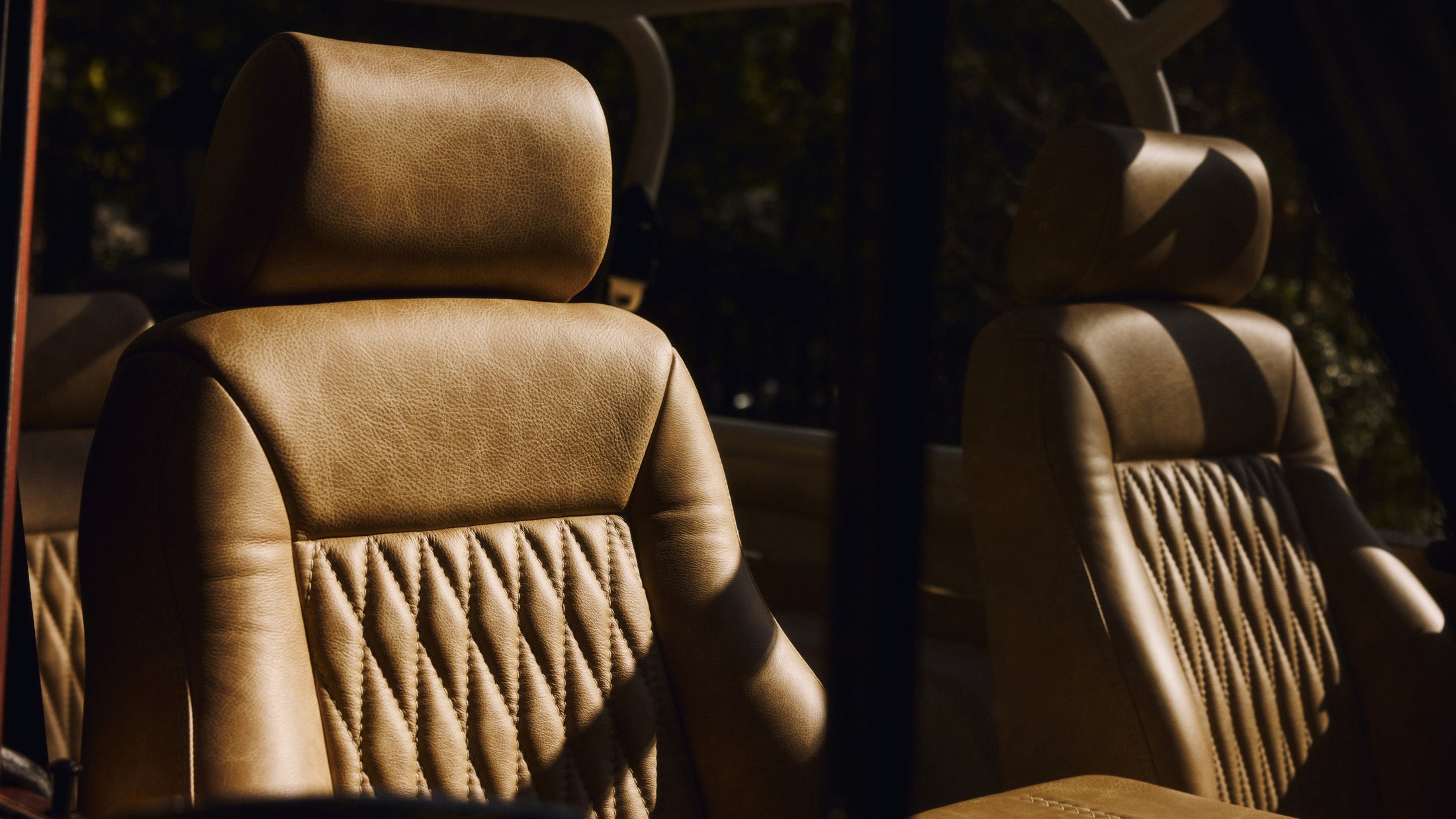 Close-up of tan leather seats inside a Classic Ford Bronco with sunlight and shadows