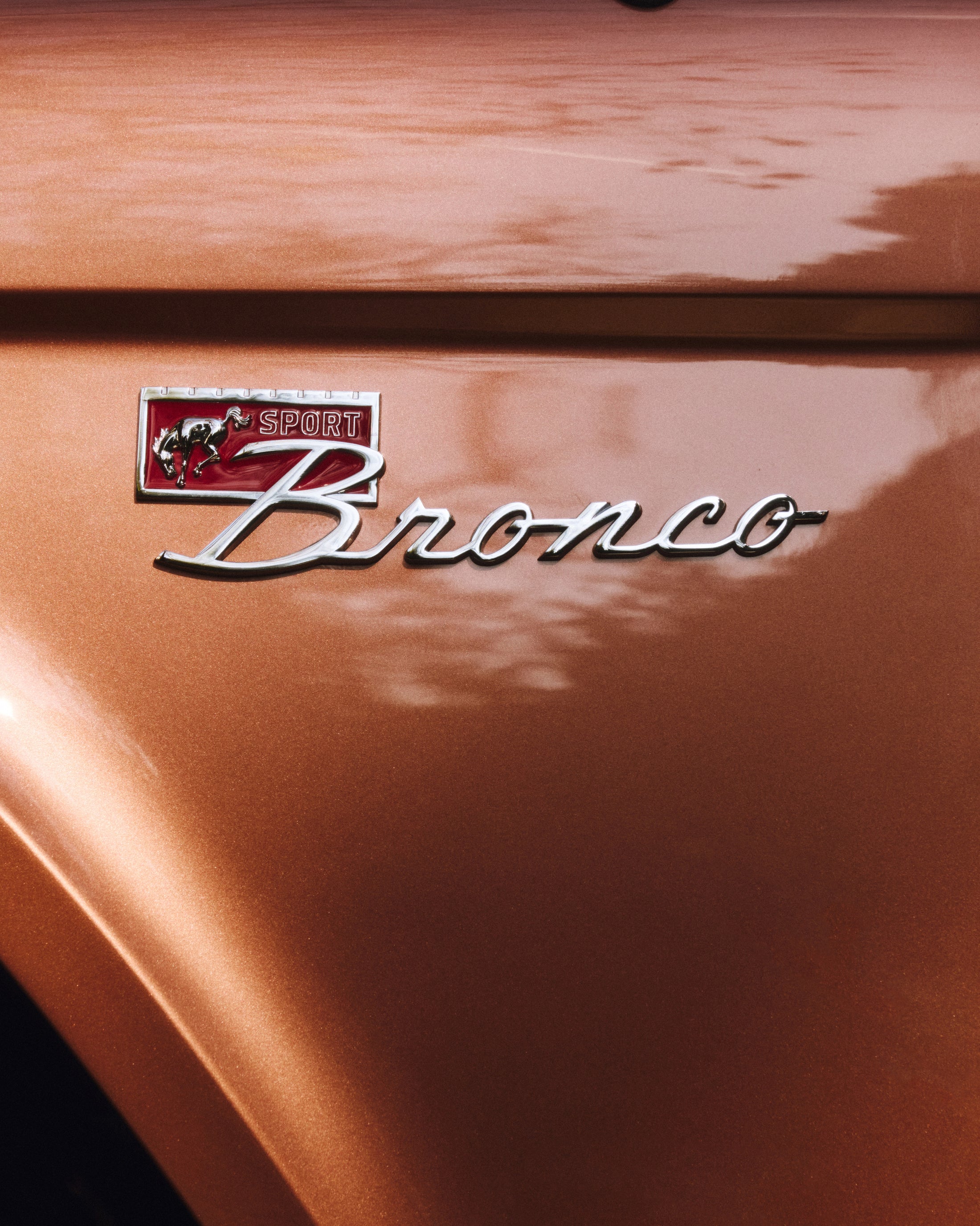 Close-up of a metallic bronze Classic Ford Bronco emblem with "Sport" and a running horse badge.