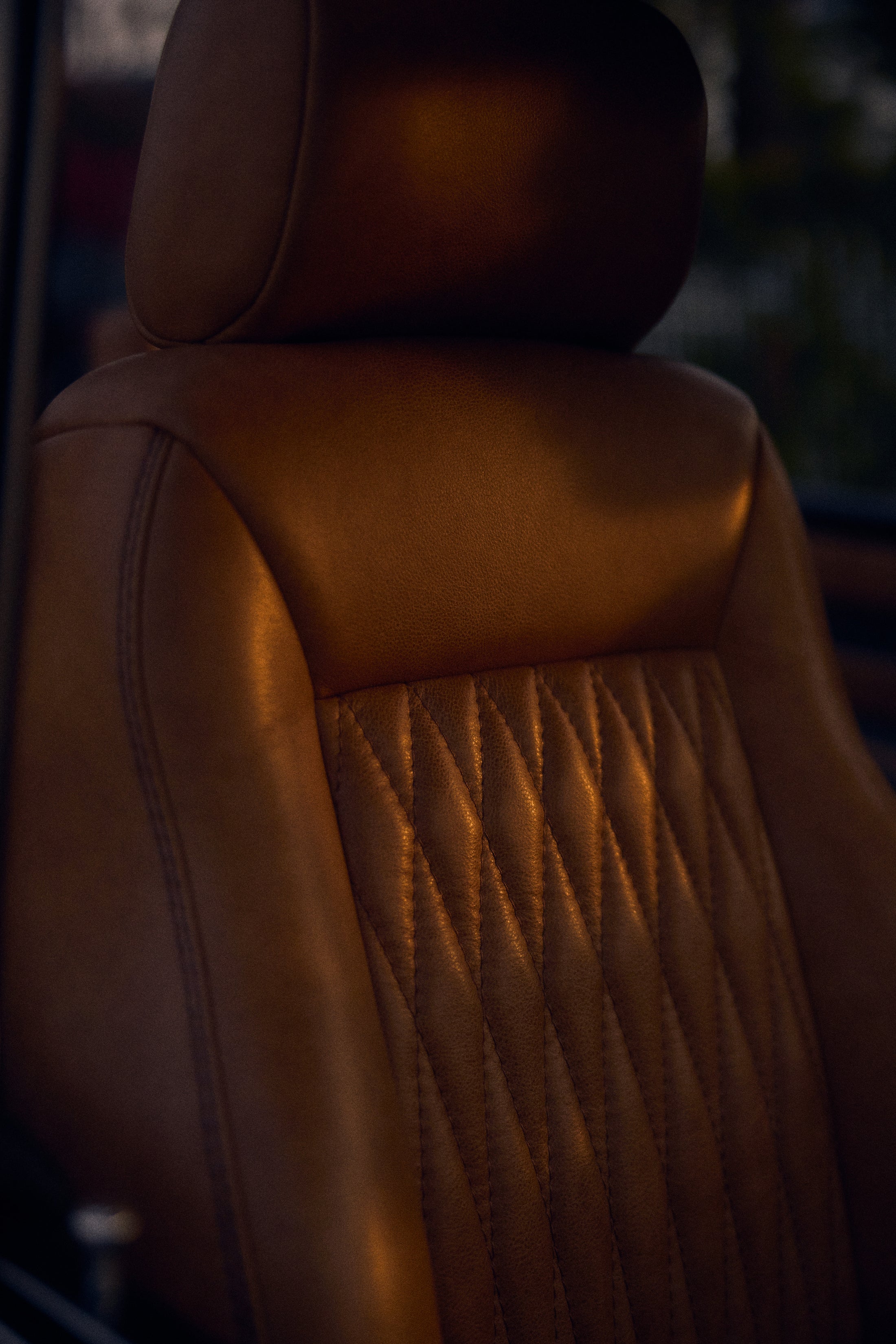 Close-up of tan leather seat upholstery with stitching in a vehicle interior.