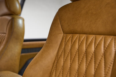 Close-up of tan leather stitched seat detail inside Classic Ford Bronco