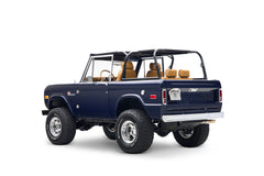 Three-quarter rear view of navy blue Classic Ford Bronco with off-road tires and tan seats