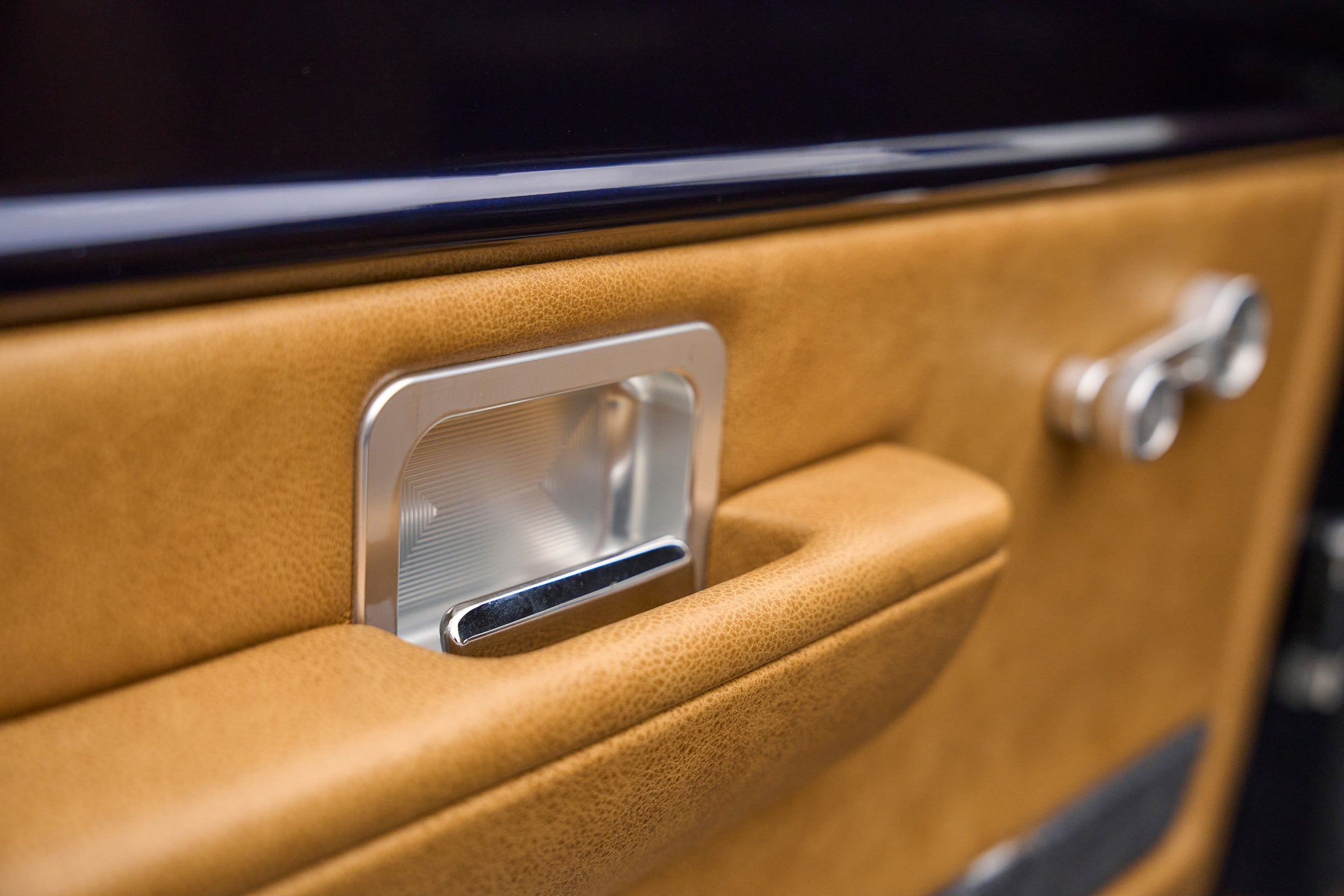 Close-up of tan door panel with chrome door handle on Classic Ford Bronco