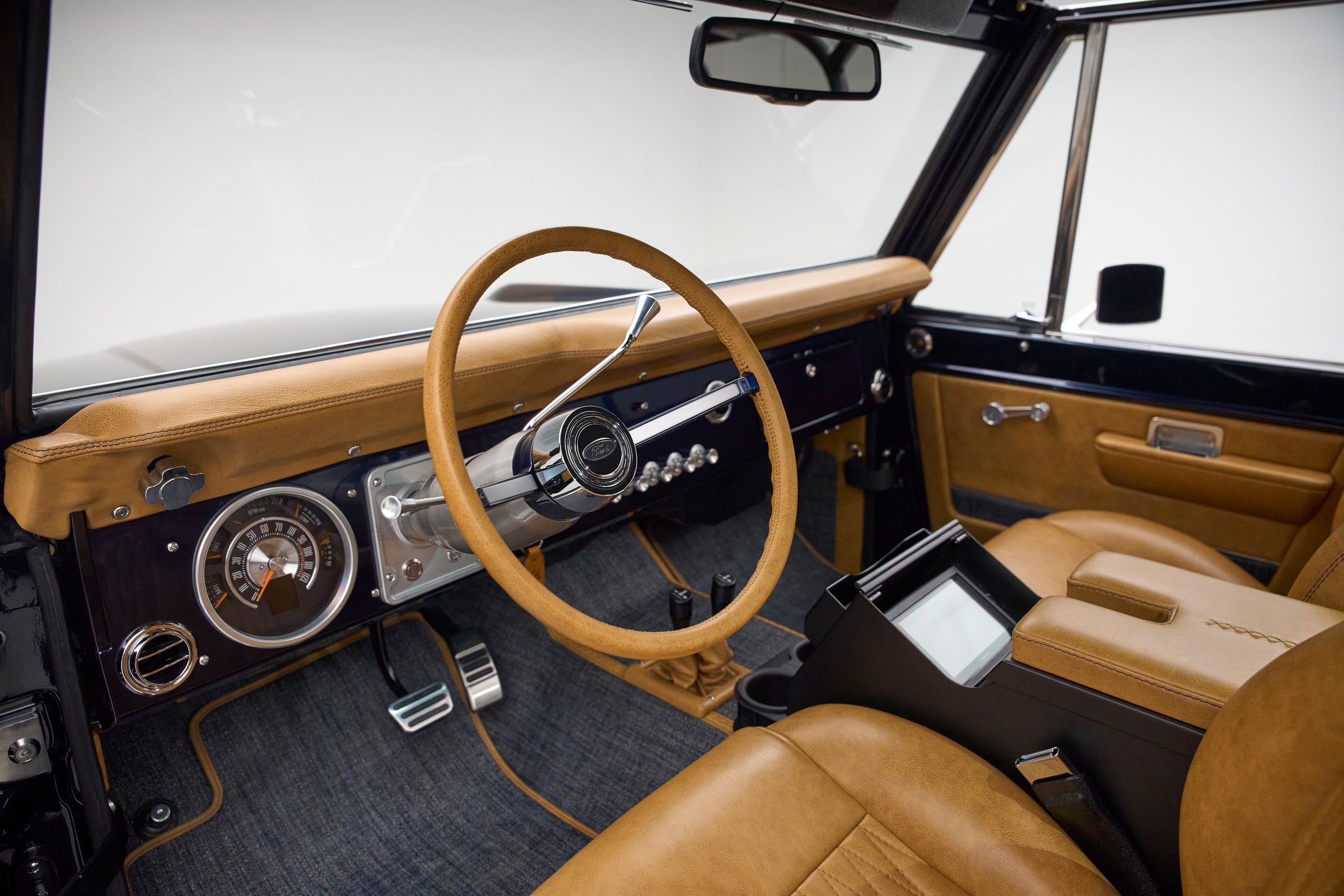 Interior view showing tan steering wheel, dashboard, and front seats of Classic Ford Bronco