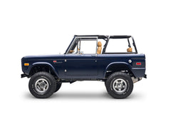 Profile view of navy blue Classic Ford Bronco with off-road tires and tan interior visible