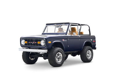 Three-quarter front view of navy blue Classic Ford Bronco, showing grille and tan interior