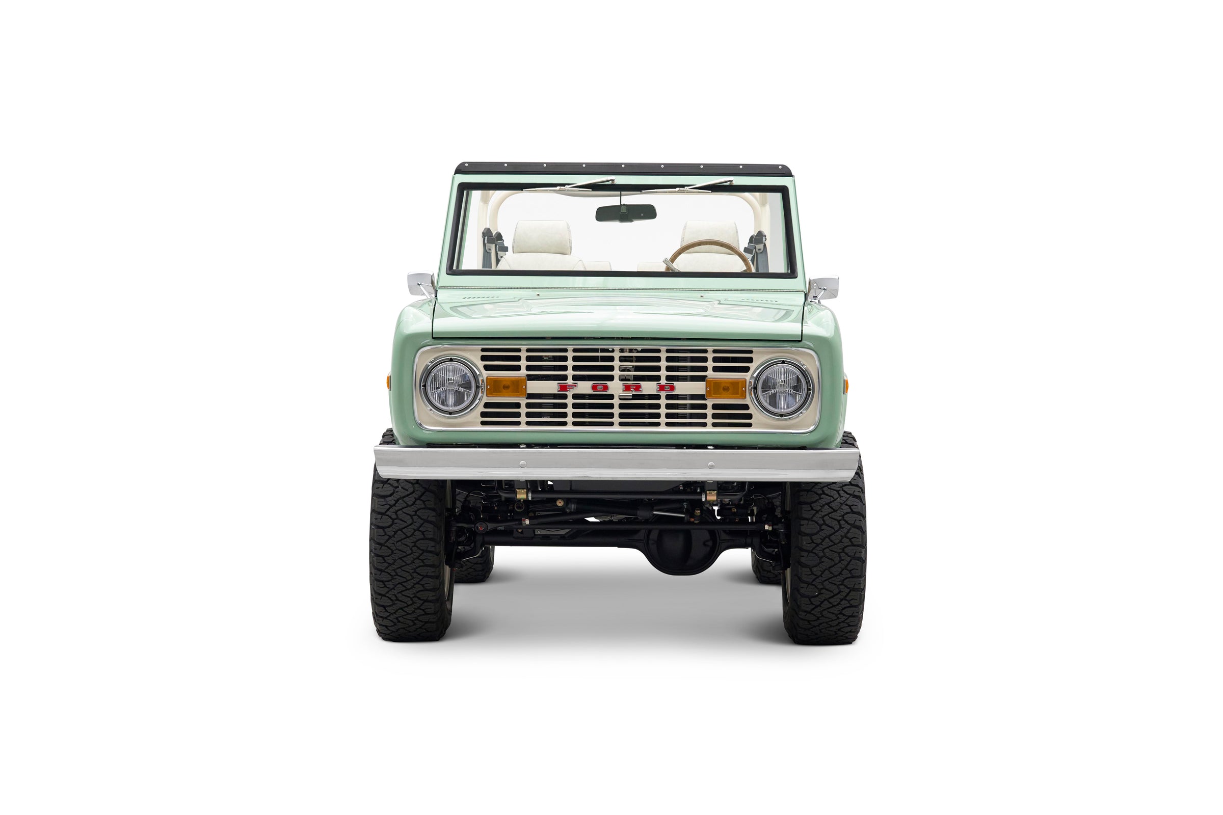 Front view of light green Classic Ford Bronco with round headlights and off-road tires