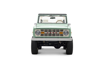 Front view of light green Classic Ford Bronco with round headlights and off-road tires
