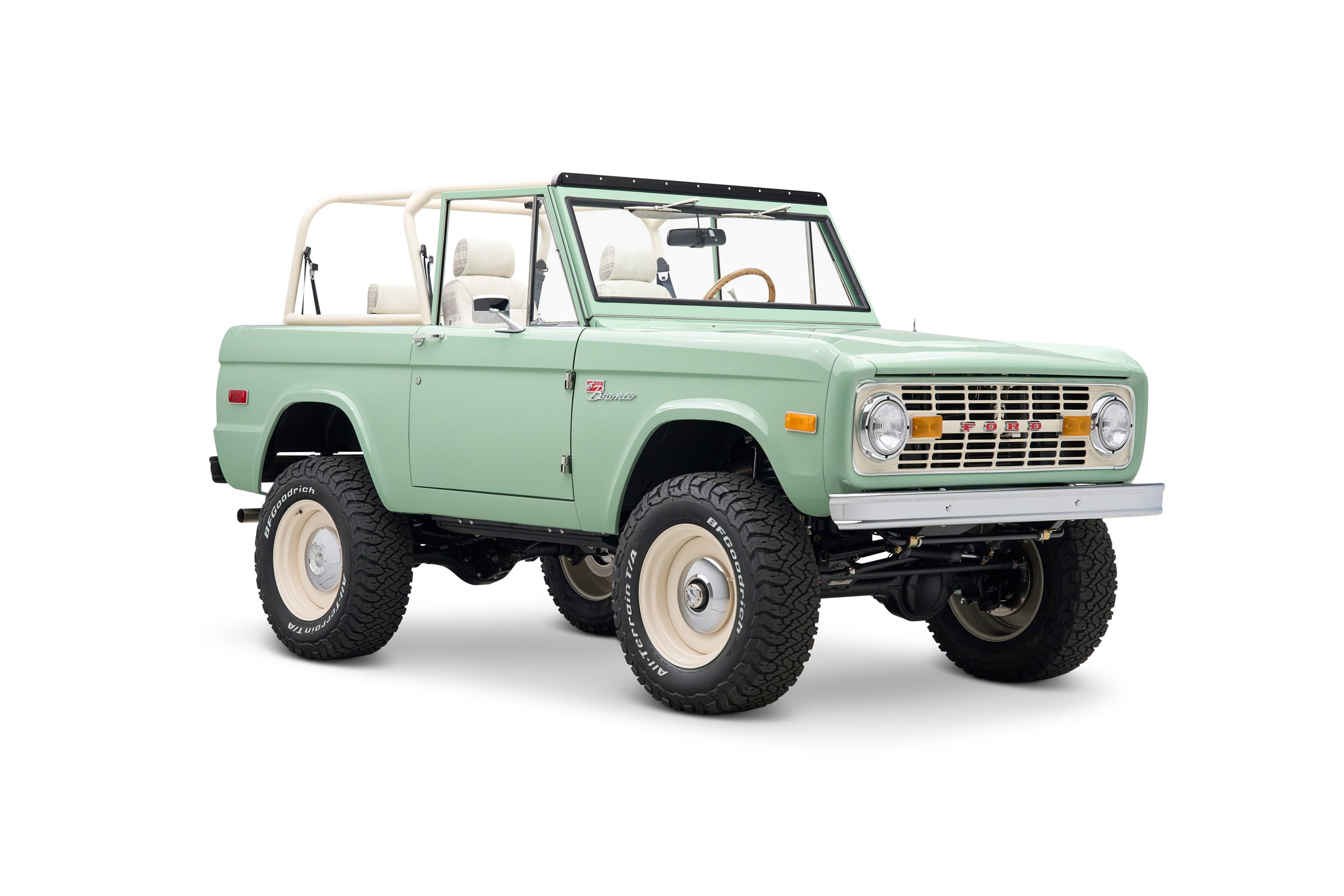 Side rear three-quarter view of Classic Ford Bronco in light green with white roll cage