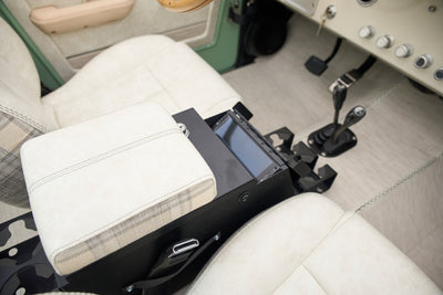 Center console with plaid and cream armrest, gear shifters and seats in classic Ford Bronco.