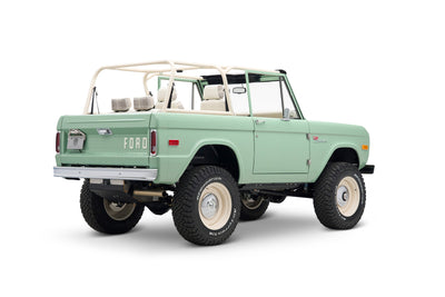 Front three-quarter view of light green Classic Ford Bronco with white roll cage and off-road tires