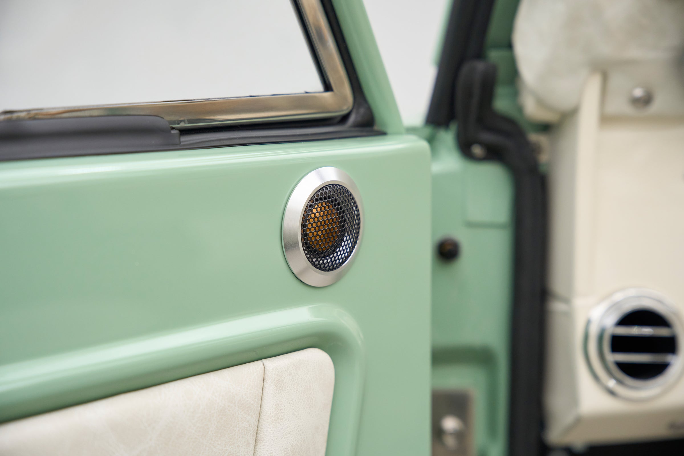 Circular speaker mounted on green door panel inside classic Ford Bronco.