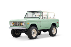 Front three-quarter view of light green Classic Ford Bronco with Ford grille and off-road tires