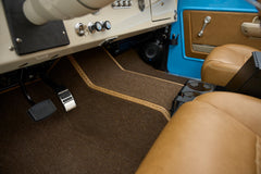 Close-up of driver side floor area with pedals and brown carpet mat in Classic Ford Bronco