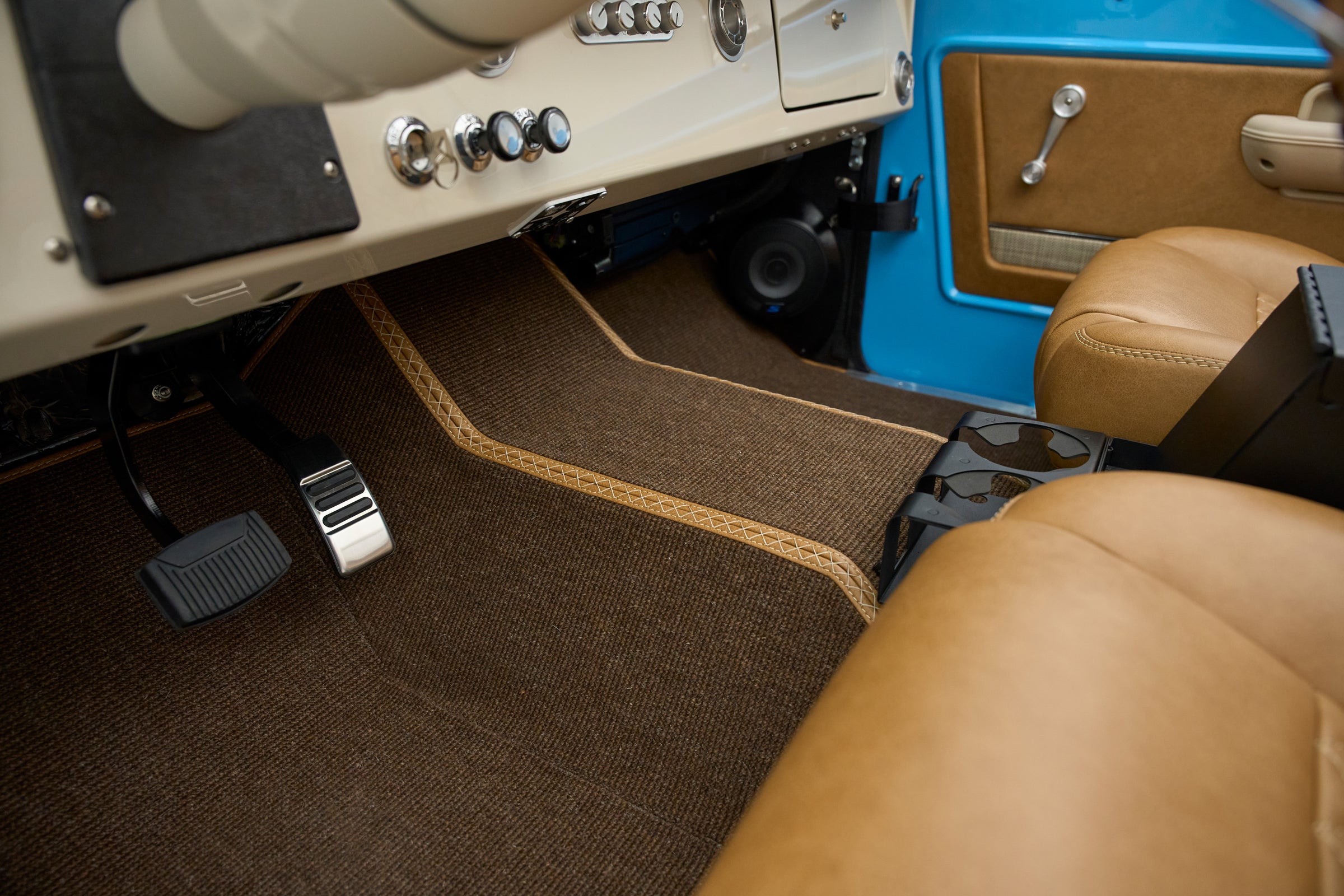 Close-up of driver side floor area with pedals and brown carpet mat in Classic Ford Bronco