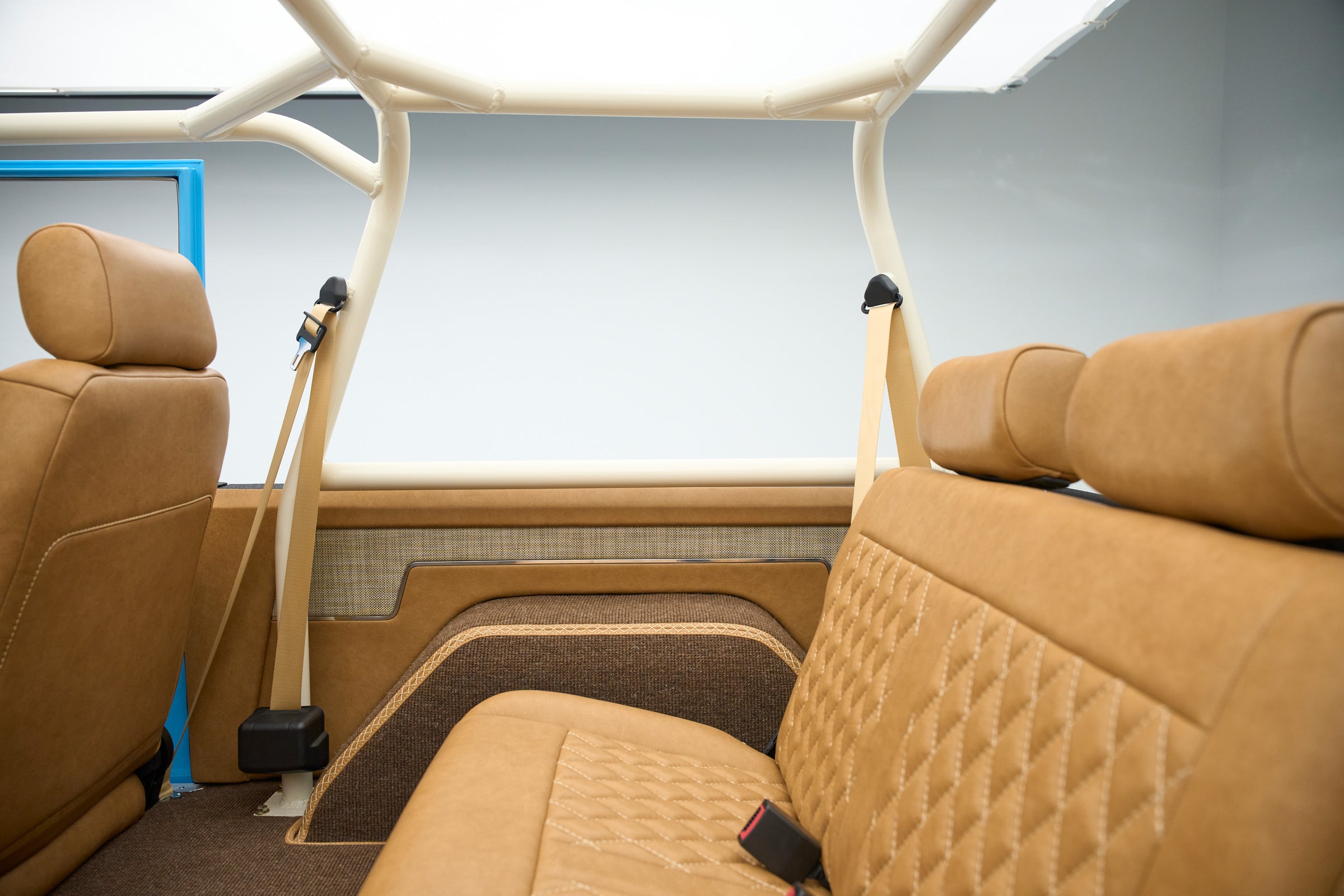 Back seat interior of Classic Ford Bronco with tan leather and patterned door panel