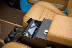 Open lockbox compartment inside center console of Classic Ford Bronco with tan seats