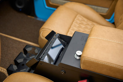 Open lockbox compartment inside center console of Classic Ford Bronco with tan seats
