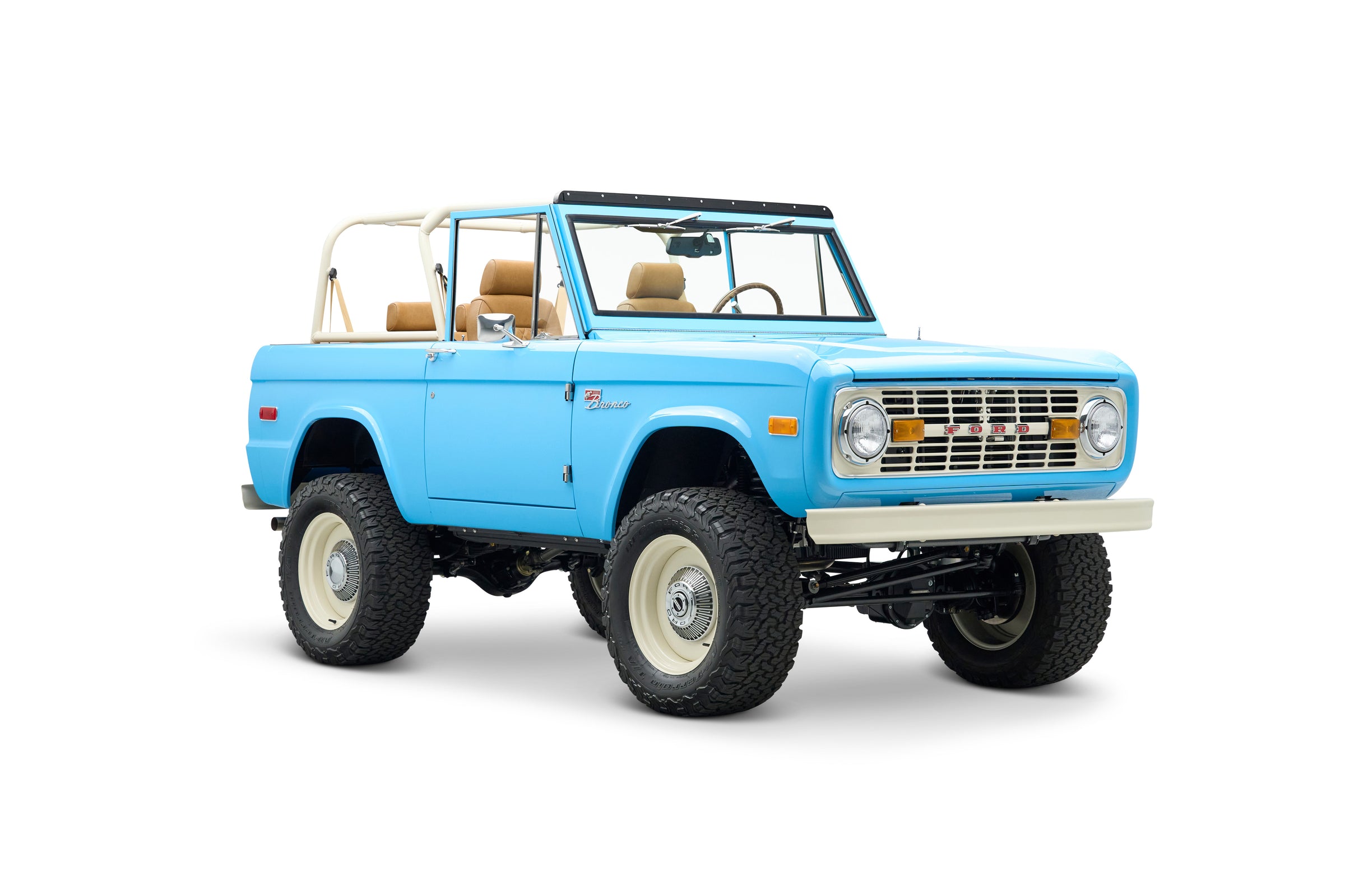 Side front angle view of light blue Classic Ford Bronco with beige roll cage and seats